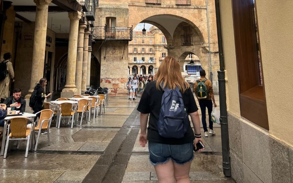 Learn English speaking confidence through immersive travel, student exploring Salamanca's historic stone archways independently