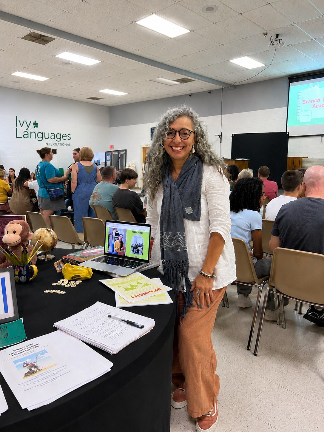 Spanish teacher at enrollment fair booth, demonstrating improving listening skills for intermediates through immersive language programs.