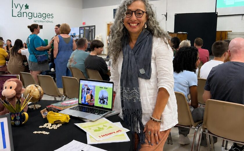 Spanish teacher at enrollment fair booth, demonstrating improving listening skills for intermediates through immersive language programs.