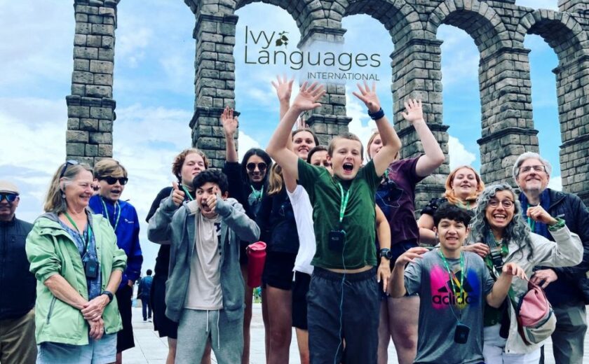 Students practicing complex sentence structures in Spanish during an exciting group trip to the Roman Aqueduct of Segovia.