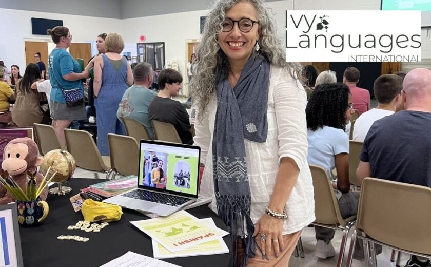 Spanish teacher at enrollment fair booth, demonstrating improving listening skills for intermediates through immersive language programs.