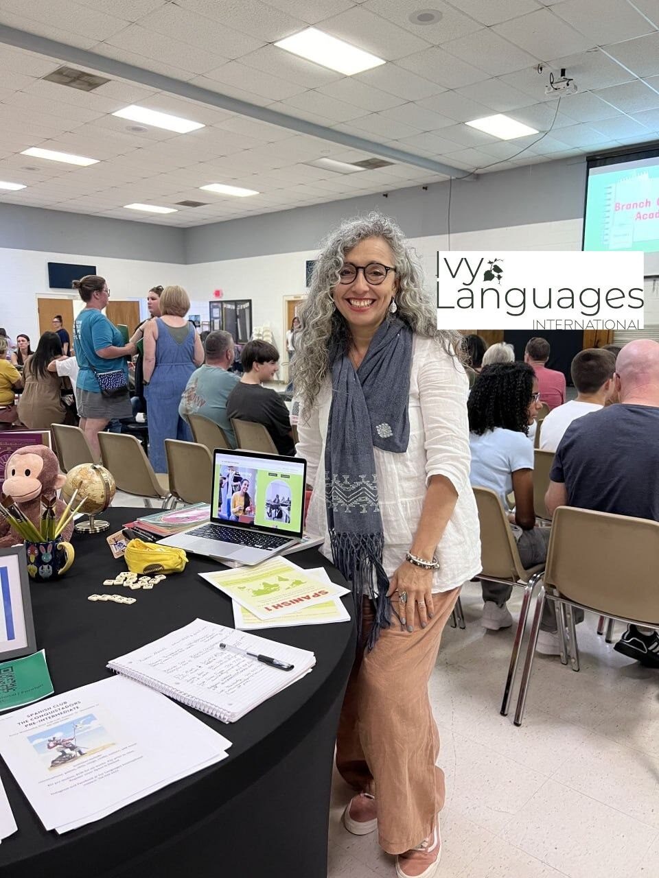 Spanish teacher at enrollment fair booth, demonstrating improving listening skills for intermediates through immersive language programs.