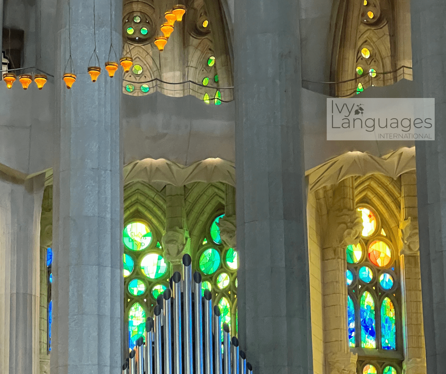 Pipe organ surrounded by vibrant stained glass windows, aid for understanding English cultural references.